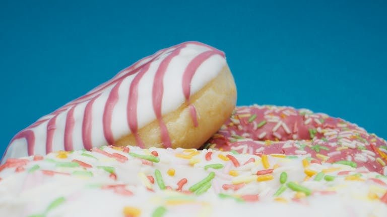 Delicious close-up of colorful doughnuts with icing and sprinkles on a bright backdrop.