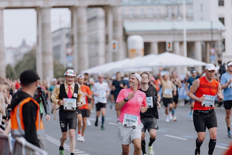 Diverse group of runners competing in marathon near iconic monument, capturing a lively and energetic atmosphere.