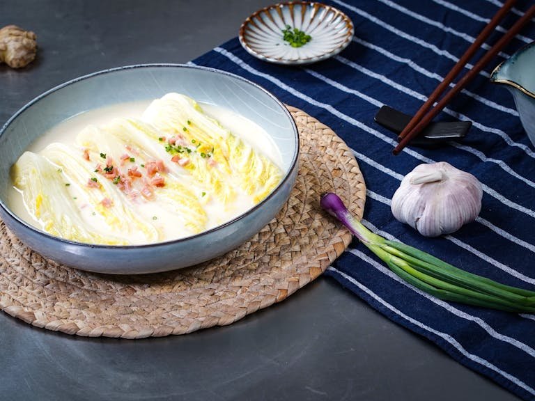 Traditional Asian cuisine featuring a cabbage coconut soup, garnished with garlic and chives.